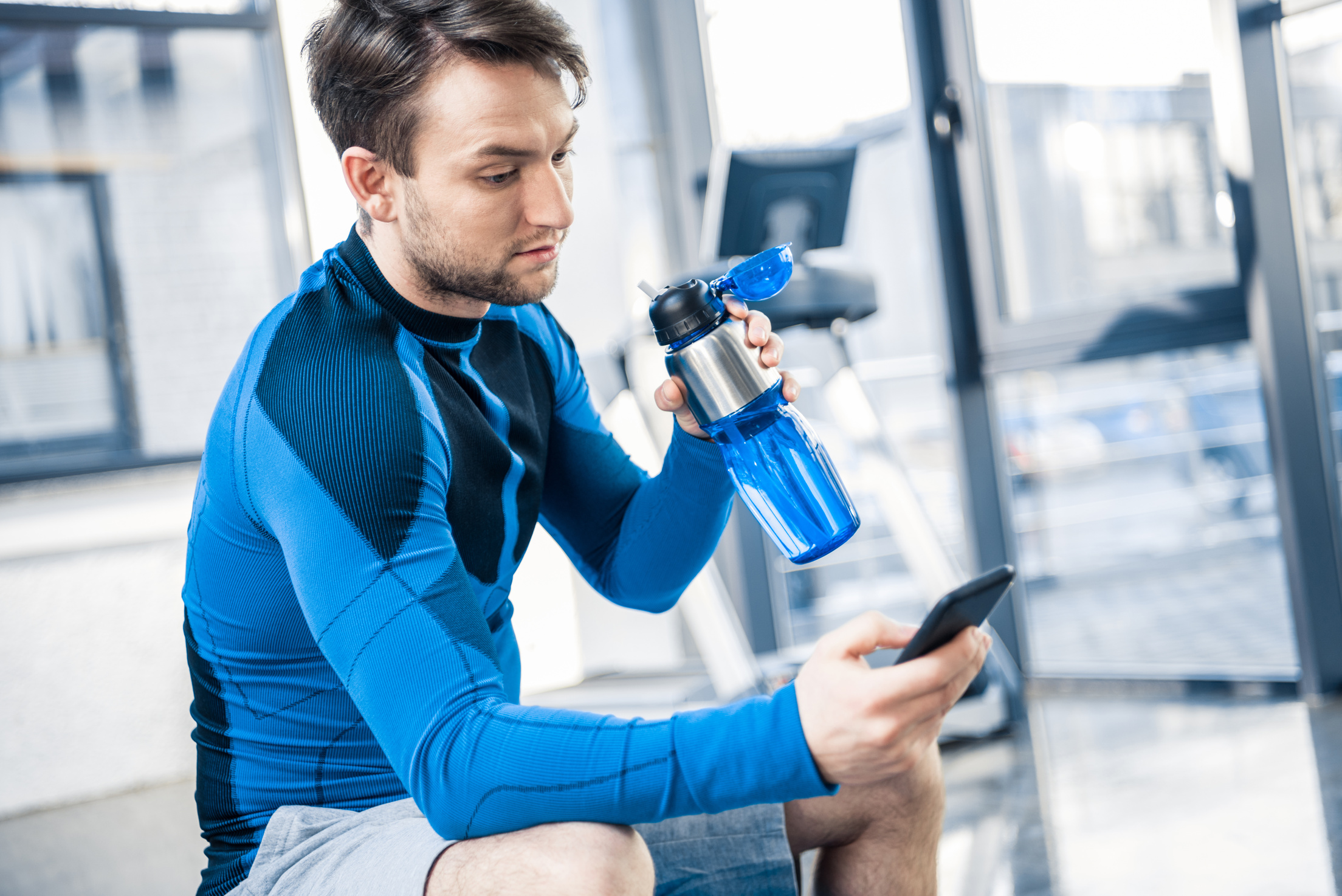 Handsome young man using smartphone at gym